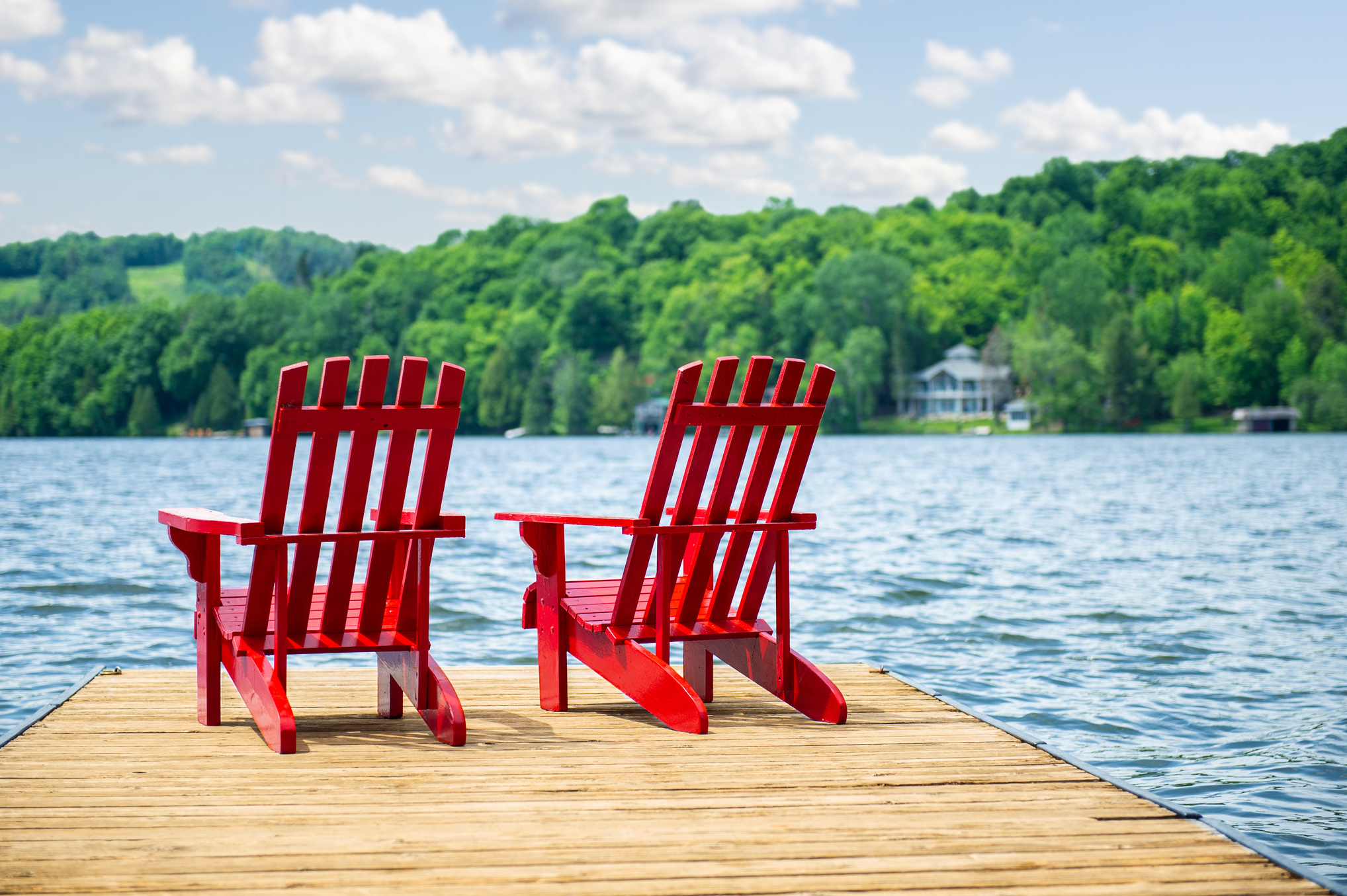 Red Muskoka chairs on a wooden dock